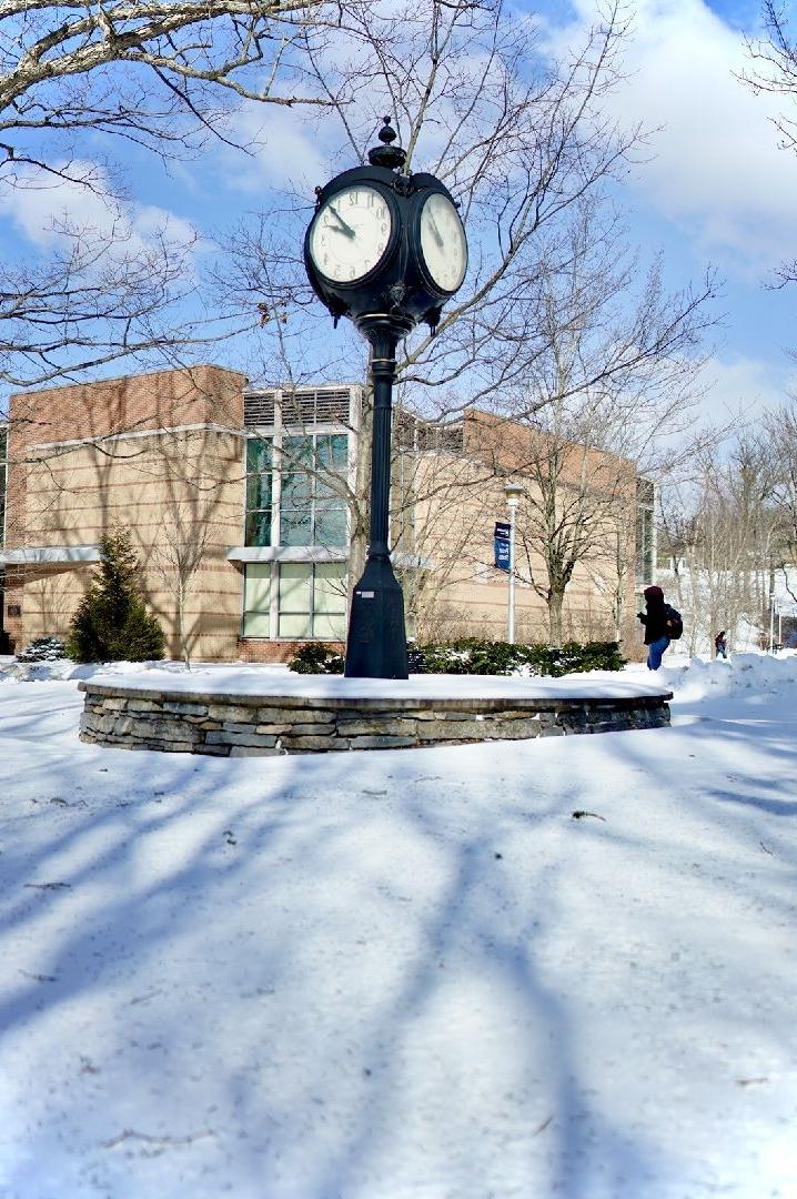 A clock tower on a sunny day with snow on the ground